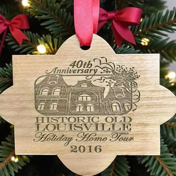 Wooden ornament with engraved text and house illustration on a Christmas tree.