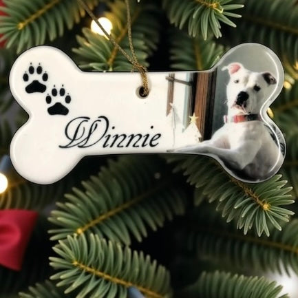 Dog bone-shaped ornament with 'Dinnie' and a dog's photo on a Christmas tree.