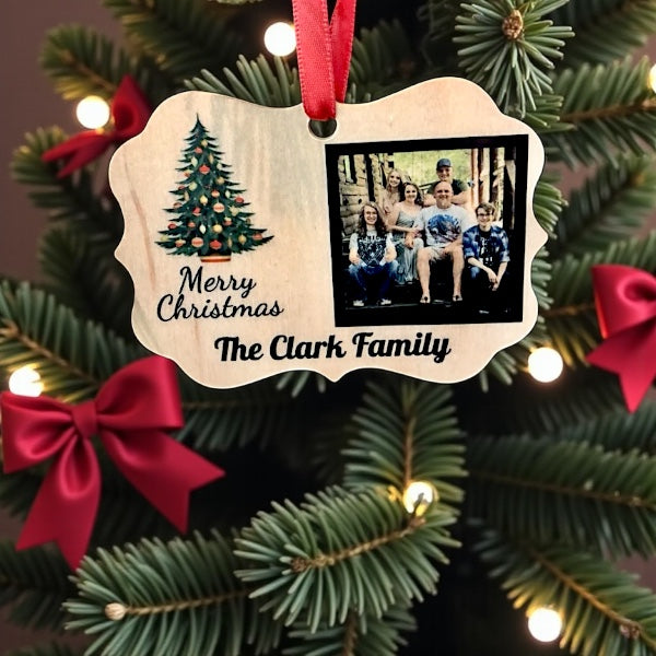 Personalized Christmas ornament with family photo and 'Merry Christmas The Clark Family' text, hanging on a decorated tree.