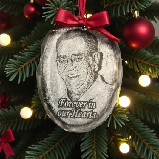 Decorative ornament with a portrait and 'Forever in our Hearts' text on a Christmas tree.