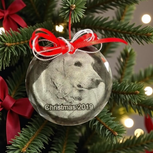 Decorative ornament with a dog's face on a Christmas tree with red ribbons and lights.