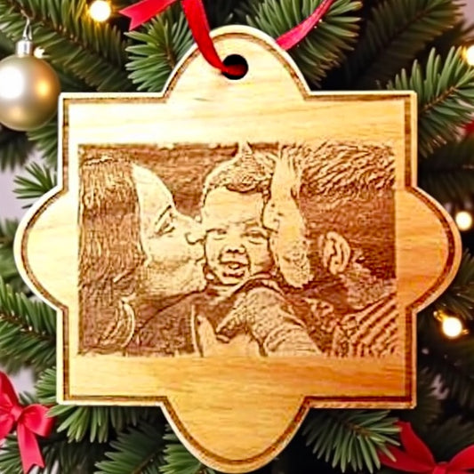 Wooden ornament with engraved photo of a child and adult on a Christmas tree.