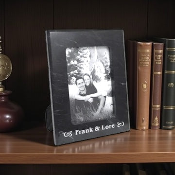 Solid black photo frame with a picture of a couple on a wooden shelf with books