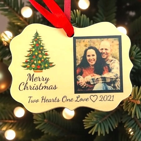 Christmas ornament with a couple's photo and festive design on a tree.